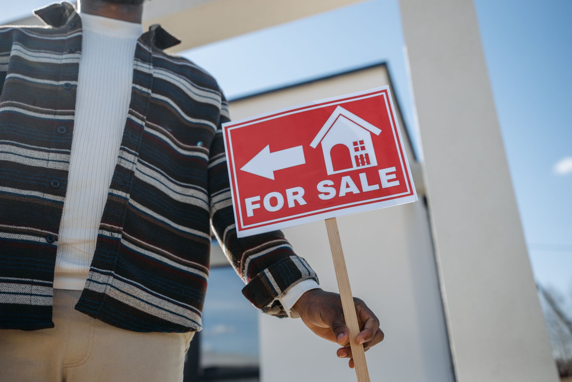 Image of a diverse couple reviewing property documents with a real estate agent in front of a Kenyan home.